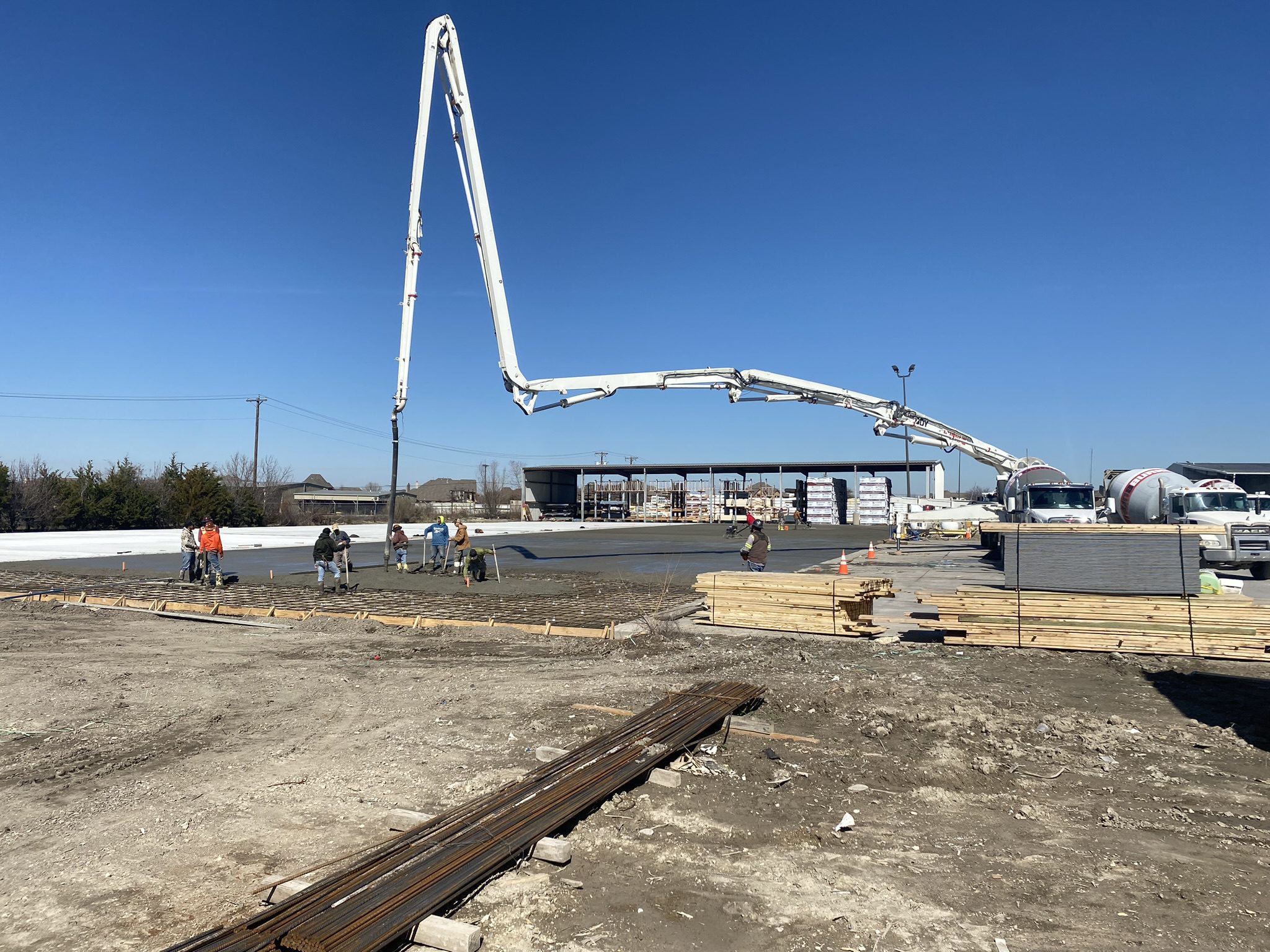 Concrete pump truck pouring slab at construction site