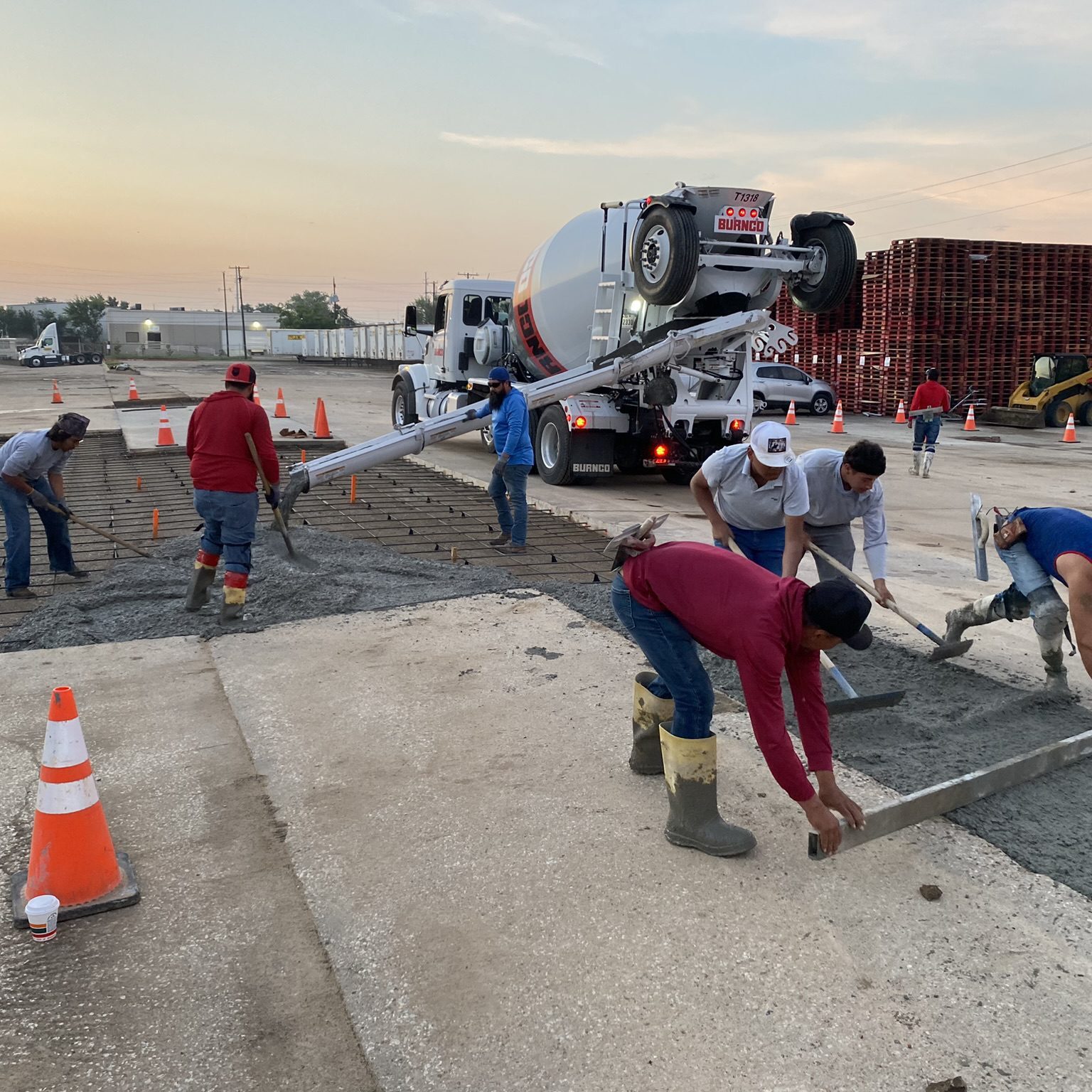 Workers pouring and leveling concrete slab